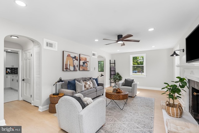 3500 The Alameda, Baltimore, MD 21218 - living area featuring arched walkways, light wood-style flooring, a fireplace with flush hearth, ceiling fan, and recessed lighting