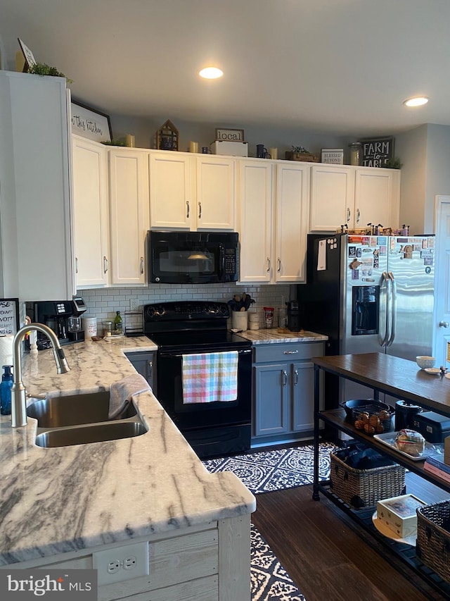 kitchen featuring white cabinets, tasteful backsplash, a sink, dark wood finished floors, and black appliances