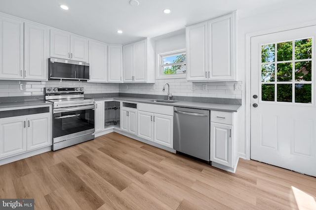 kitchen with a sink, white cabinets, stainless steel appliances, and light wood-type flooring