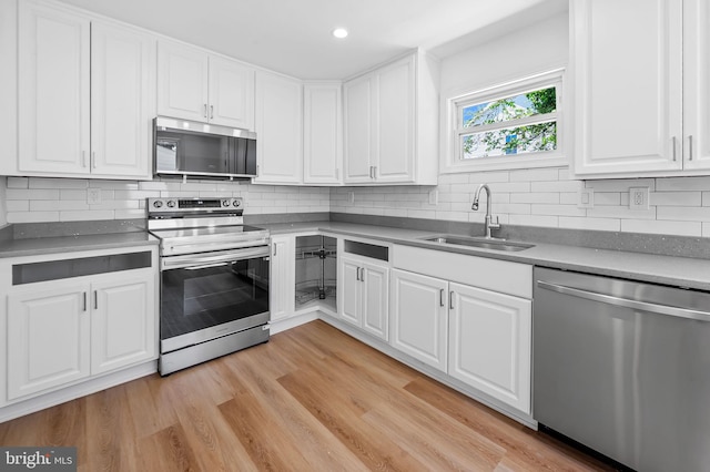 kitchen with a sink, appliances with stainless steel finishes, white cabinets, and decorative backsplash