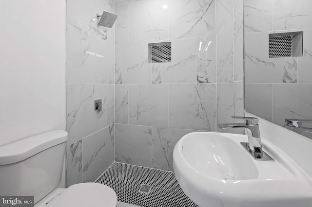 full bathroom with a sink, toilet, and tiled shower