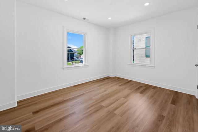 spare room with a wealth of natural light, recessed lighting, wood finished floors, and visible vents