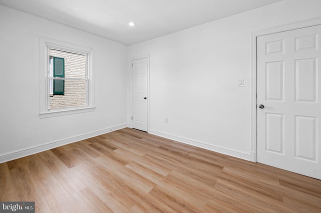 empty room with light wood-style floors, baseboards, and recessed lighting