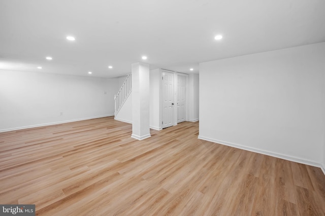 finished below grade area featuring stairway, baseboards, light wood-type flooring, and recessed lighting