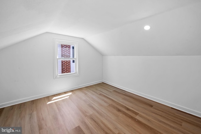 additional living space with baseboards, vaulted ceiling, and wood finished floors
