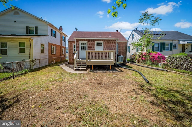 rear view of house featuring a fenced backyard, a wooden deck, a yard, and brick siding