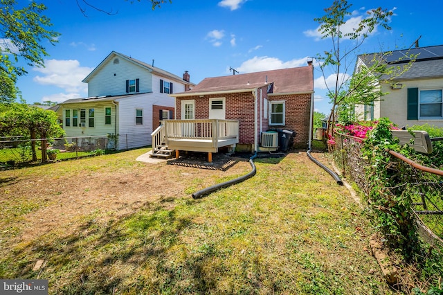 rear view of house featuring a fenced backyard, a wooden deck, a yard, and brick siding