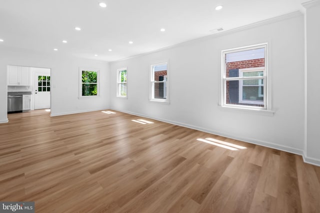 unfurnished living room with a healthy amount of sunlight, ornamental molding, recessed lighting, and visible vents