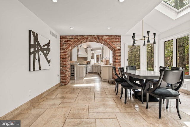 dining area featuring arched walkways, recessed lighting, baseboards, a skylight, and visible vents