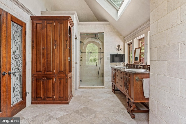 bathroom with double vanity, a shower stall, a sink, and vaulted ceiling with skylight
