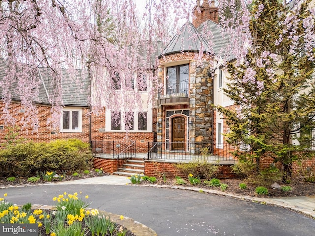 view of front of house featuring brick siding and a balcony
