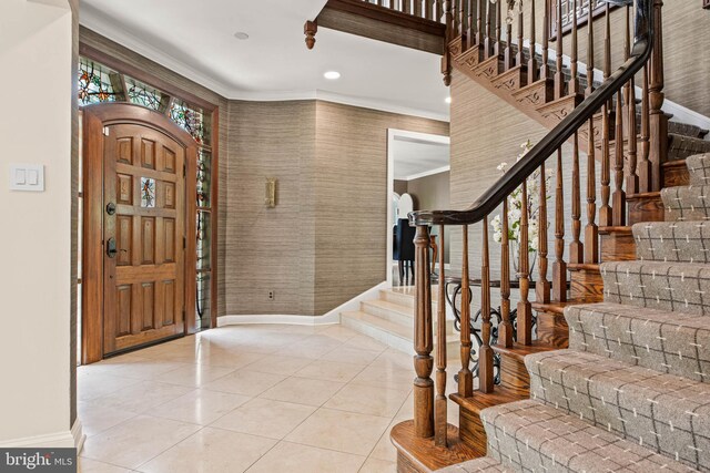 tiled foyer featuring baseboards, wallpapered walls, ornamental molding, and stairway