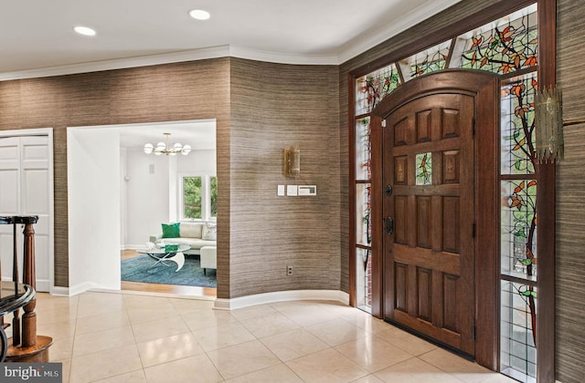 entryway with baseboards, ornamental molding, a chandelier, and light tile patterned flooring