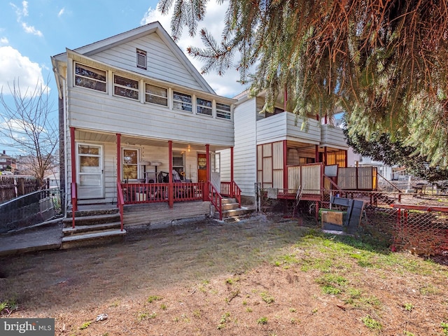 back of property with fence and covered porch