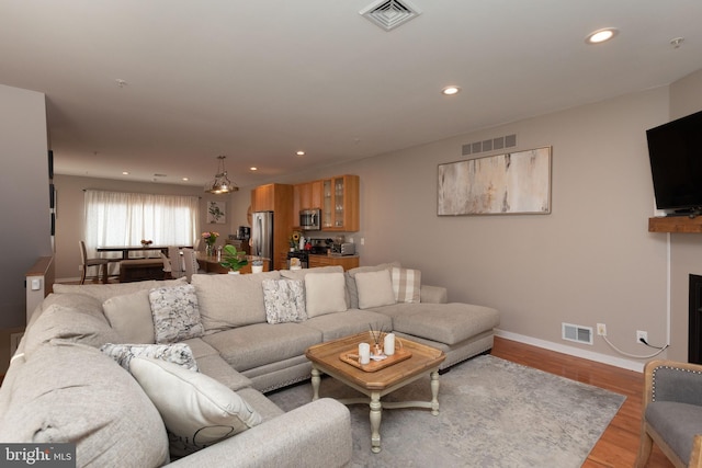 living room featuring recessed lighting, visible vents, and wood finished floors
