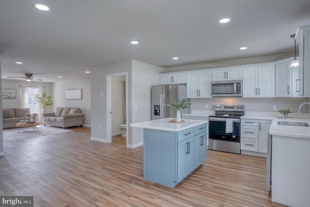 kitchen with a kitchen island, a sink, light countertops, open floor plan, and stainless steel appliances