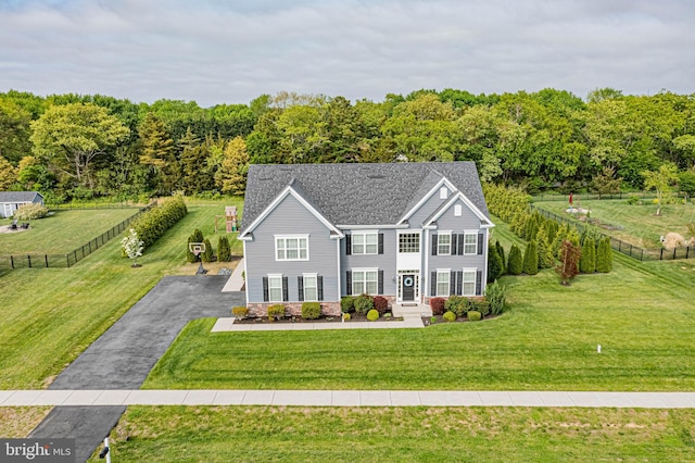 view of front facade with a front lawn, fence, and aphalt driveway