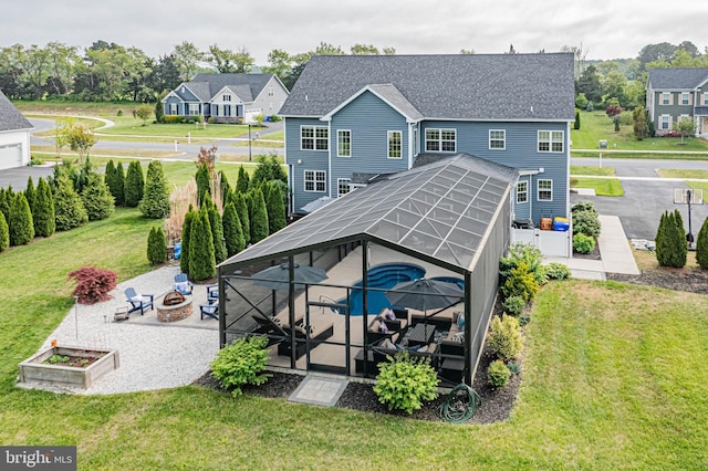 rear view of house with a lanai, a patio, a fire pit, and a lawn
