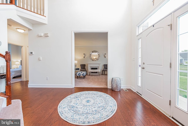 entrance foyer with baseboards, hardwood / wood-style floors, and a high ceiling