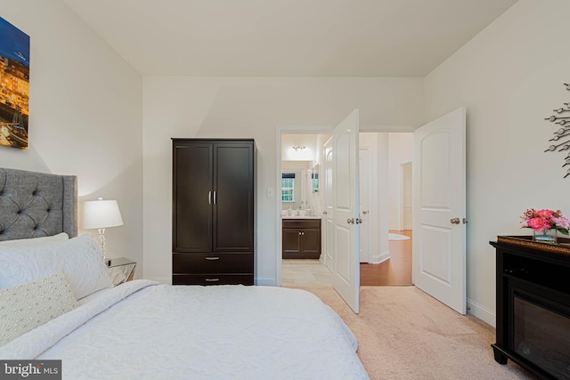 bedroom featuring light carpet, ensuite bathroom, and baseboards