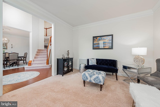carpeted living area with baseboards, ornamental molding, and stairway