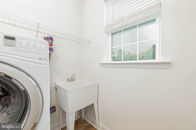washroom with baseboards, washer / dryer, and laundry area