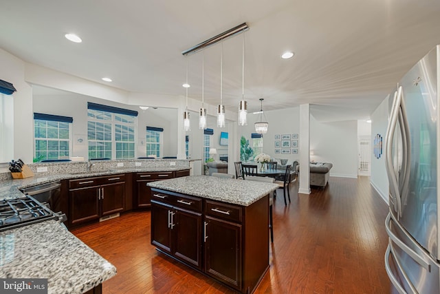 kitchen with freestanding refrigerator, light stone counters, open floor plan, and dark wood-style floors