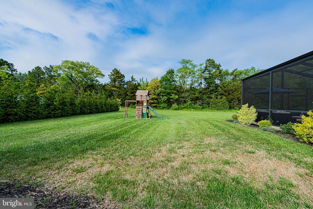 view of yard featuring a playground and glass enclosure