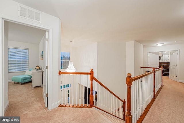 corridor with baseboards, an upstairs landing, visible vents, and carpet