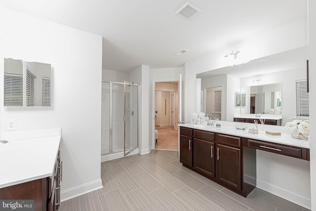 full bathroom featuring a stall shower, baseboards, vanity, and visible vents