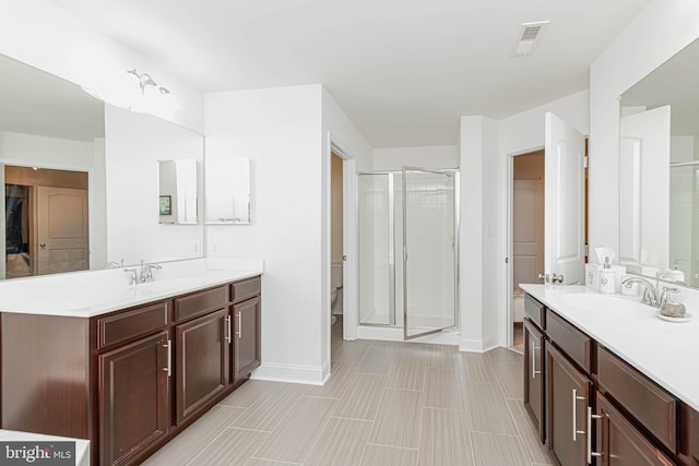 full bathroom with visible vents, a stall shower, two vanities, and a sink
