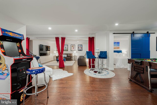 playroom featuring baseboards, recessed lighting, a barn door, and hardwood / wood-style flooring