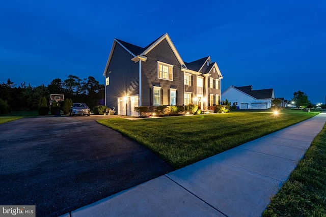 view of front of property featuring a lawn, aphalt driveway, and an attached garage