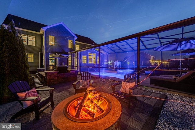 patio at twilight featuring glass enclosure, a hot tub, a fire pit, and a pool
