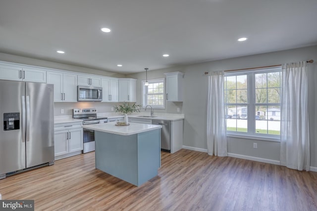 kitchen featuring light countertops, white cabinets, appliances with stainless steel finishes, and light wood finished floors