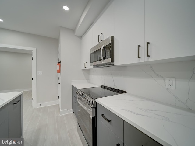 kitchen featuring light stone countertops, gray cabinets, stainless steel appliances, baseboards, and recessed lighting