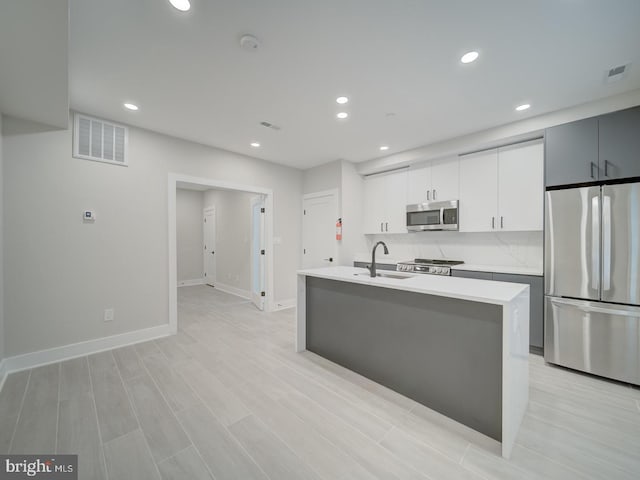 kitchen with light countertops, stainless steel appliances, visible vents, and a sink