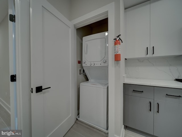 laundry room with cabinet space and stacked washer / dryer
