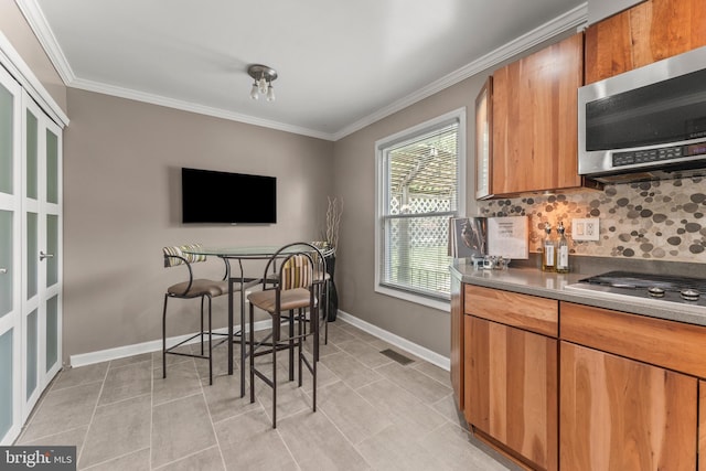 kitchen with tasteful backsplash, crown molding, appliances with stainless steel finishes, visible vents, and baseboards