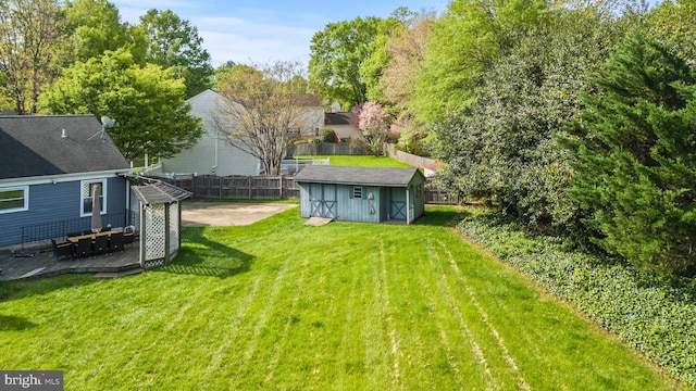 view of yard featuring an outdoor structure, a shed, a wooden deck, and a fenced backyard