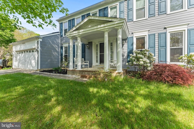 colonial house featuring driveway, covered porch, an attached garage, and a front lawn