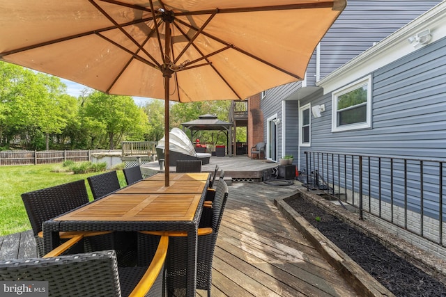 wooden terrace featuring fence, a gazebo, and outdoor dining area