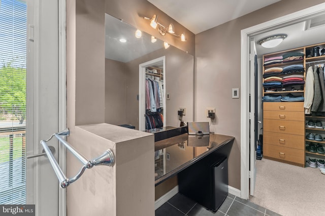 bathroom featuring tile patterned floors, a spacious closet, and baseboards