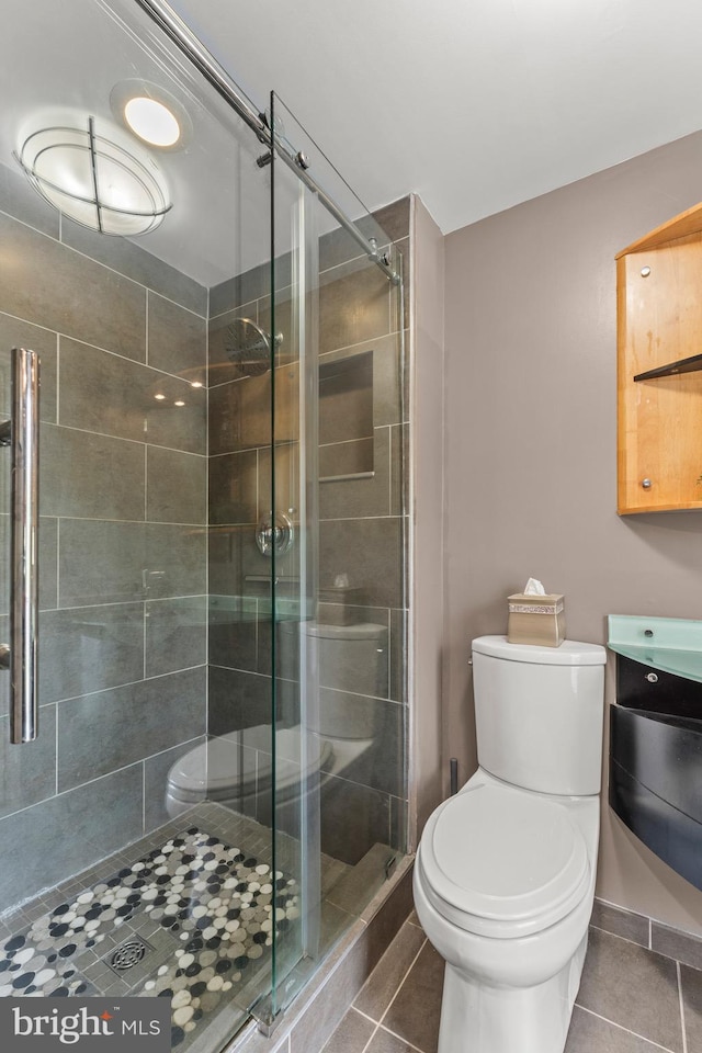 full bathroom with tile patterned floors, a stall shower, and toilet