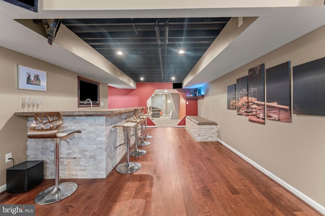bar featuring recessed lighting, wet bar, wood finished floors, and baseboards