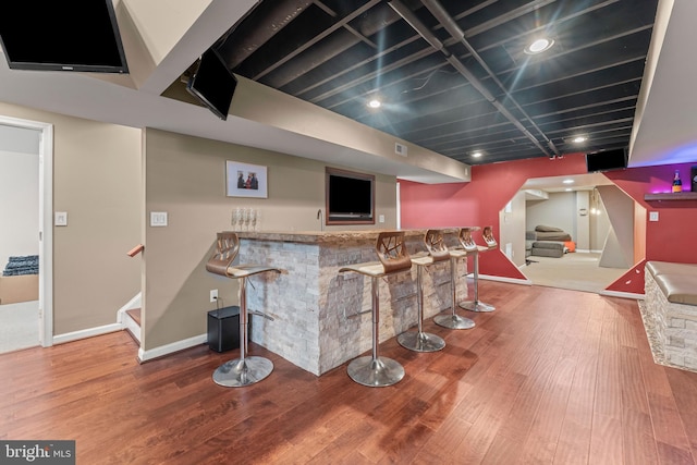 bar featuring stairway, visible vents, a community bar, baseboards, and wood finished floors