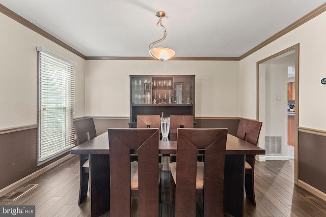 dining room featuring baseboards, visible vents, and crown molding