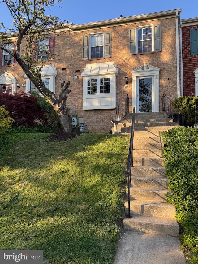 townhome / multi-family property with brick siding and a front lawn