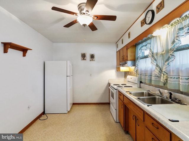kitchen with white appliances, under cabinet range hood, brown cabinetry, and a sink