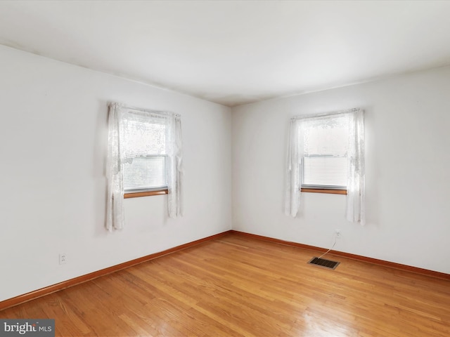 unfurnished room with visible vents, light wood-style flooring, and baseboards